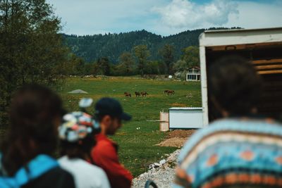 Rear view of people on field against trees