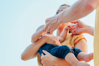 Midsection of couple holding hands against sky