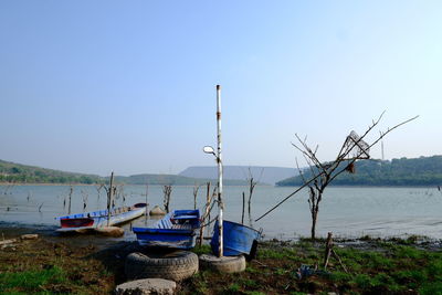 Sailboats moored on beach against clear sky