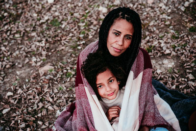 Portrait of smiling daughter sitting with mother on land