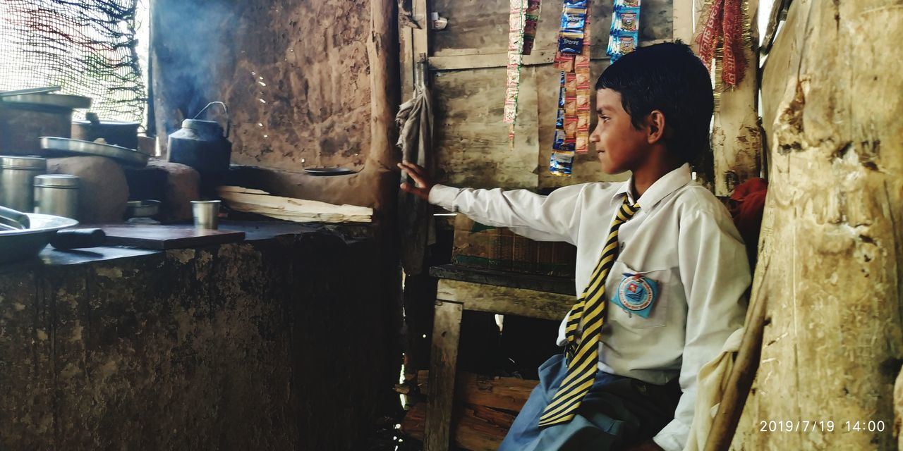 SIDE VIEW OF A YOUNG MAN STANDING BY BUILT STRUCTURE