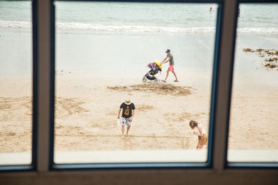 People at beach seen through window