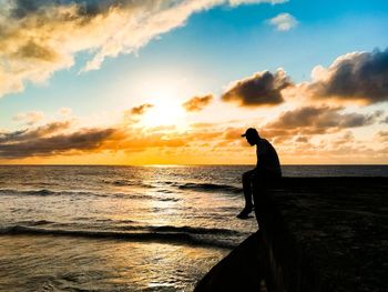 Man on beach against sky during sunset