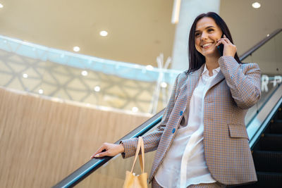 Smiling young woman using mobile phone while standing outdoors