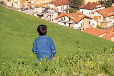 Rear view of man on field against buildings