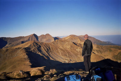 Man standing on rocky mountains against clear blue sky
