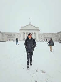 Man walking against buildings in city during winter