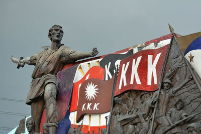 Low angle view of statue against building against sky