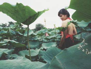 Young woman standing by plants