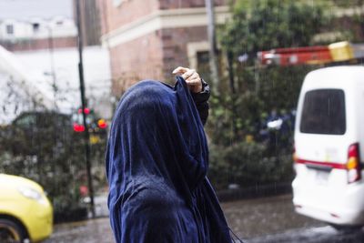 Man holding umbrella on street in city