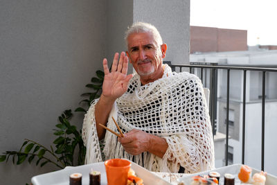 Attractive middle-aged man have fun while eating sitting at a table laid chinese  food on a terrace