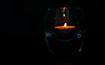 Close-up of lit candle against black background