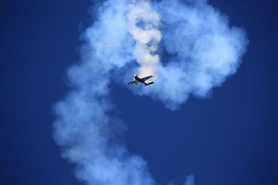 Low angle view of airplane flying against blue sky