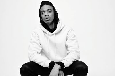 Portrait of young man sitting against white background