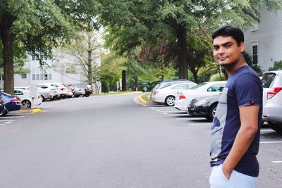 Portrait of young man standing on road in city