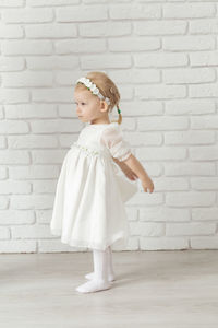 Portrait of cute girl standing against brick wall