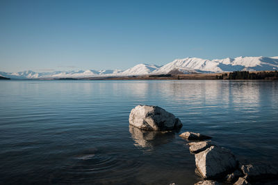 Scenic view of lake by snowcapped mountain against sky