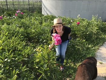 Woman with eyes closed holding flowers while standing in yard