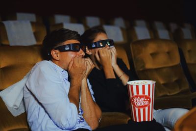 Scared couple watching movie in theater