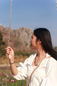 White dress asian teenage woman sitting on a swing