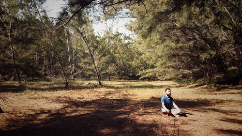 Man meditating on field in forest