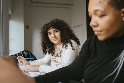 Portrait of woman with curly hair sitting by female friend in university