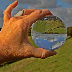 Cropped hand of woman holding crystal ball with reflection