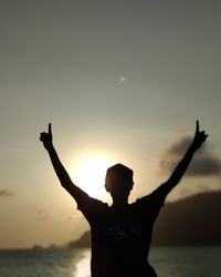 Silhouette man standing by sea against sky during sunset