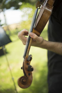 Midsection of man playing violin outdoors