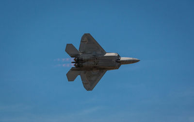 Low angle view of airplane flying against clear blue sky