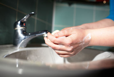 Cropped image of person washing hands in bathroom
