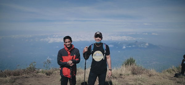 Friends standing on mountain against sky