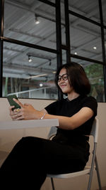 Young woman using mobile phone while sitting in cafe