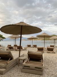 Lounge chairs and parasols on beach against sky