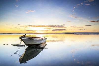 Boat moored in lake against sky during sunset