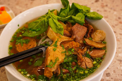Pho bo or vietnamese soup with beef and meat balls served in a white bowl at the restaurant. 