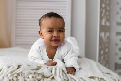 Portrait of cute baby boy on bed at home