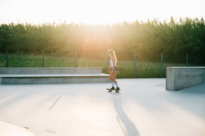 Full length of young woman skateboarding on sunny day