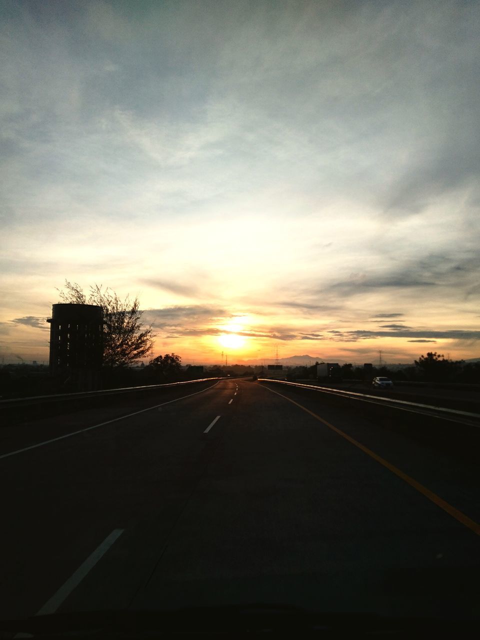 sky, transportation, sunset, road, cloud, horizon, nature, no people, light, sunlight, the way forward, mode of transportation, marking, dawn, sign, road marking, symbol, evening, car, outdoors, diminishing perspective, vanishing point, darkness, motor vehicle, travel, sun, highway, silhouette, dramatic sky, city