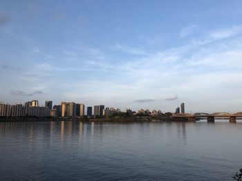 Buildings by river against sky in city