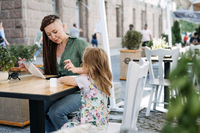 Busy successful mother and business owner with cell phone and tablet having breakfast with her