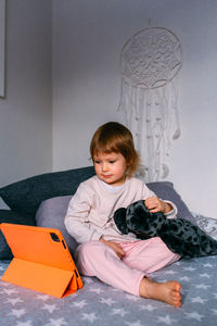 Small child watches cartoons at home on sofa on the tablet. kid use technology