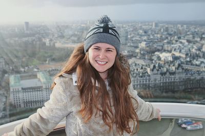 Portrait of smiling young woman in city during winter