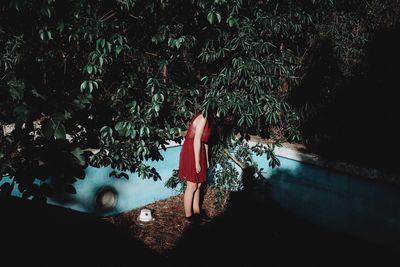 Side view of woman standing by tree