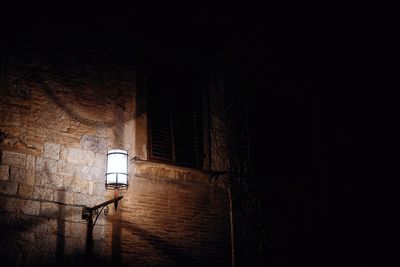 Low angle view of illuminated lamp on wall