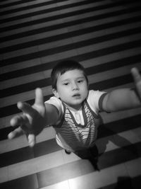 High angle portrait of boy gesturing while standing on striped floor