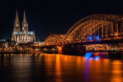 Illuminated bridge over river at night