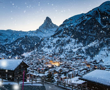 Snow covered buildings in city against sky