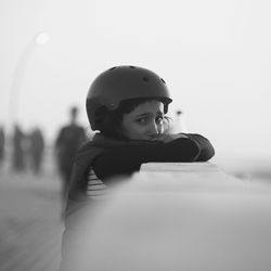 Portrait of sad girl wearing safety jacket and helmet crying while leaning on railing