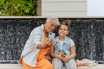 Portrait of happy grandmother and granddaughter making selfie.